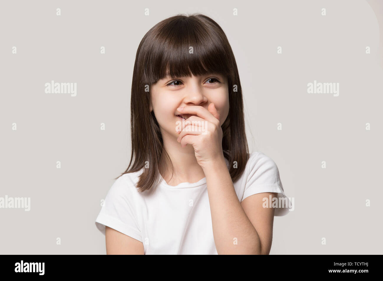 Laughing shy cute girl isolated on grey studio background Stock Photo
