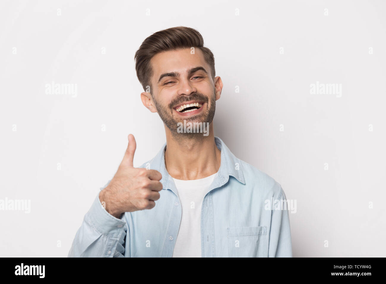 Headshot portrait happy guy showing thumbs up studio shot Stock Photo