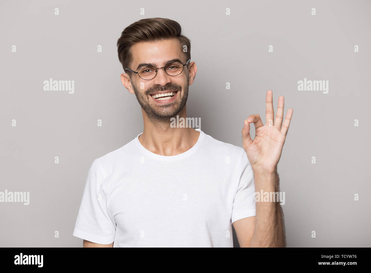 Happy guy gesturing ok sign smiling looking at camera Stock Photo