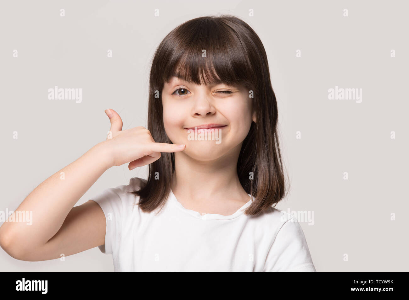 Little funny girl makes call me hand gesture studio shot Stock Photo