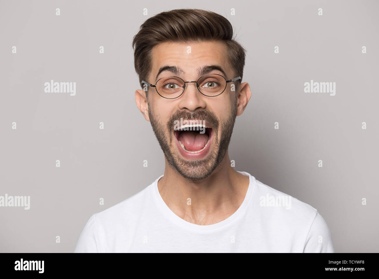 Headshot portrait funny guy wearing glasses screaming posing in studio