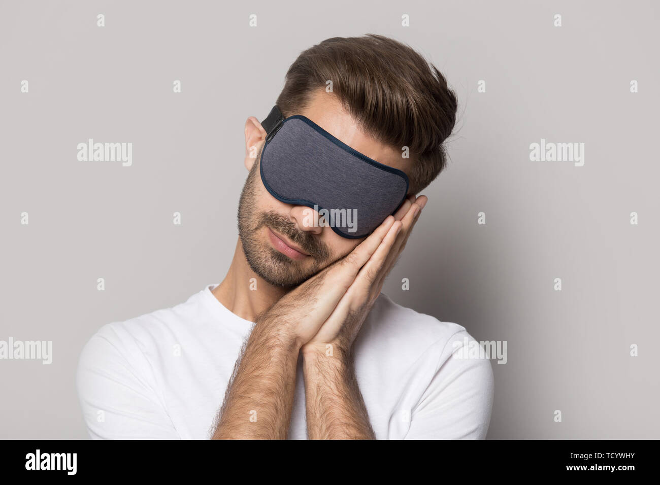 Man wearing mask sleeping on folded hands studio shot Stock Photo