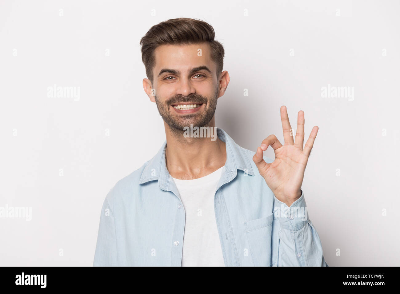 Guy with white toothy smile showing ok sign studio shot Stock Photo