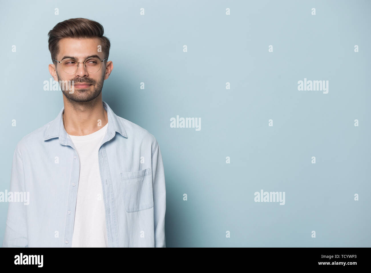 Sly guy looking aside at copyspace isolated on blue background Stock Photo
