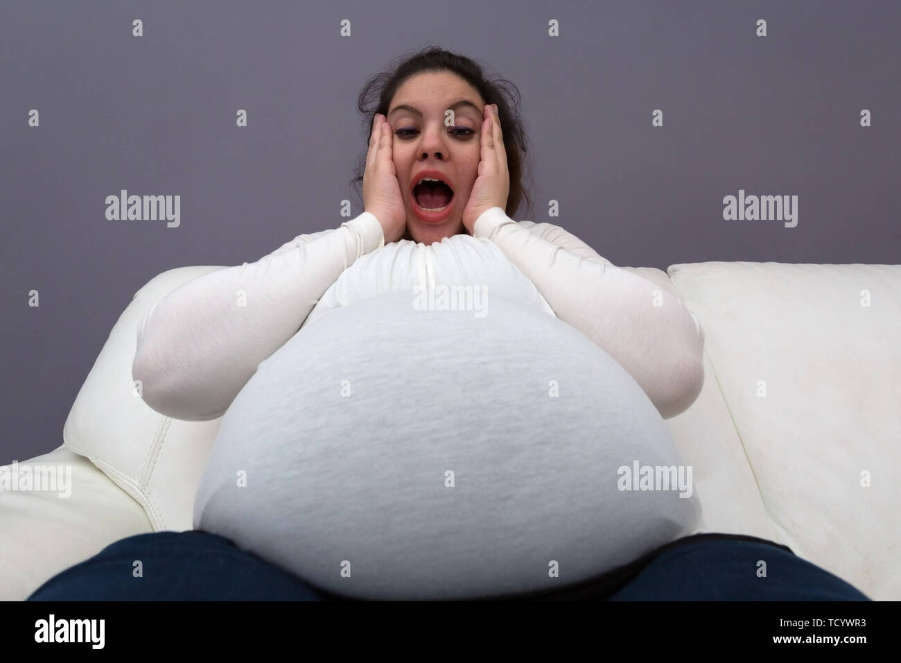Humorous shocked reaction of pregnant mom to her big growing tummy Stock Photo