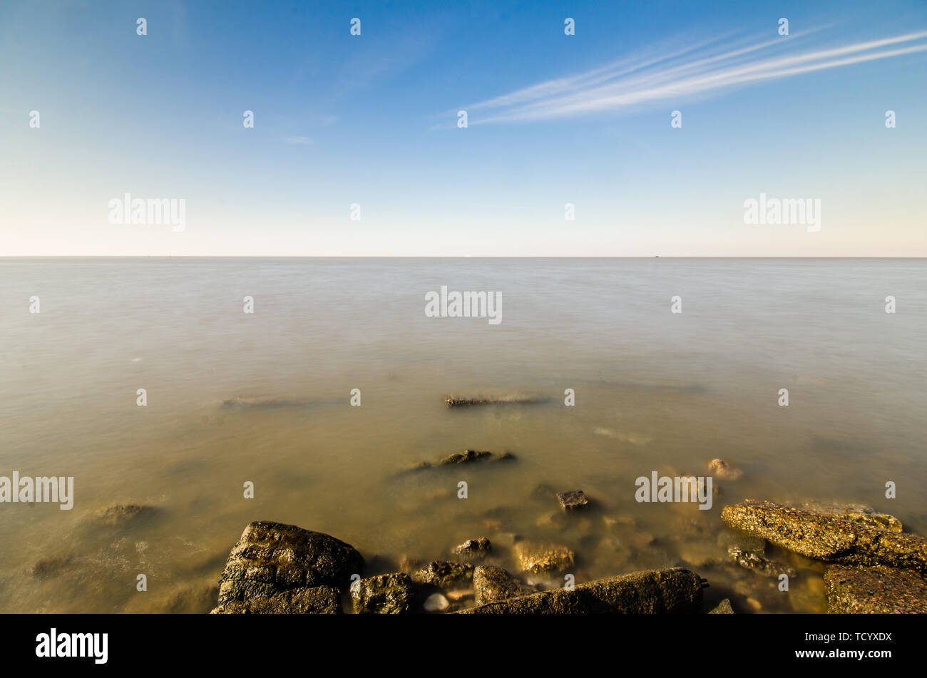 Rocky beach, sea water surface, and beautiful blue sky with clouds ...