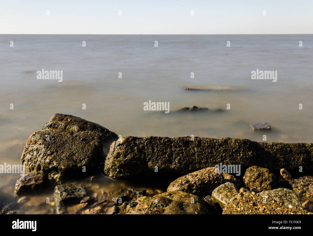 Rocky beach, sea water surface, and beautiful blue sky with clouds ...