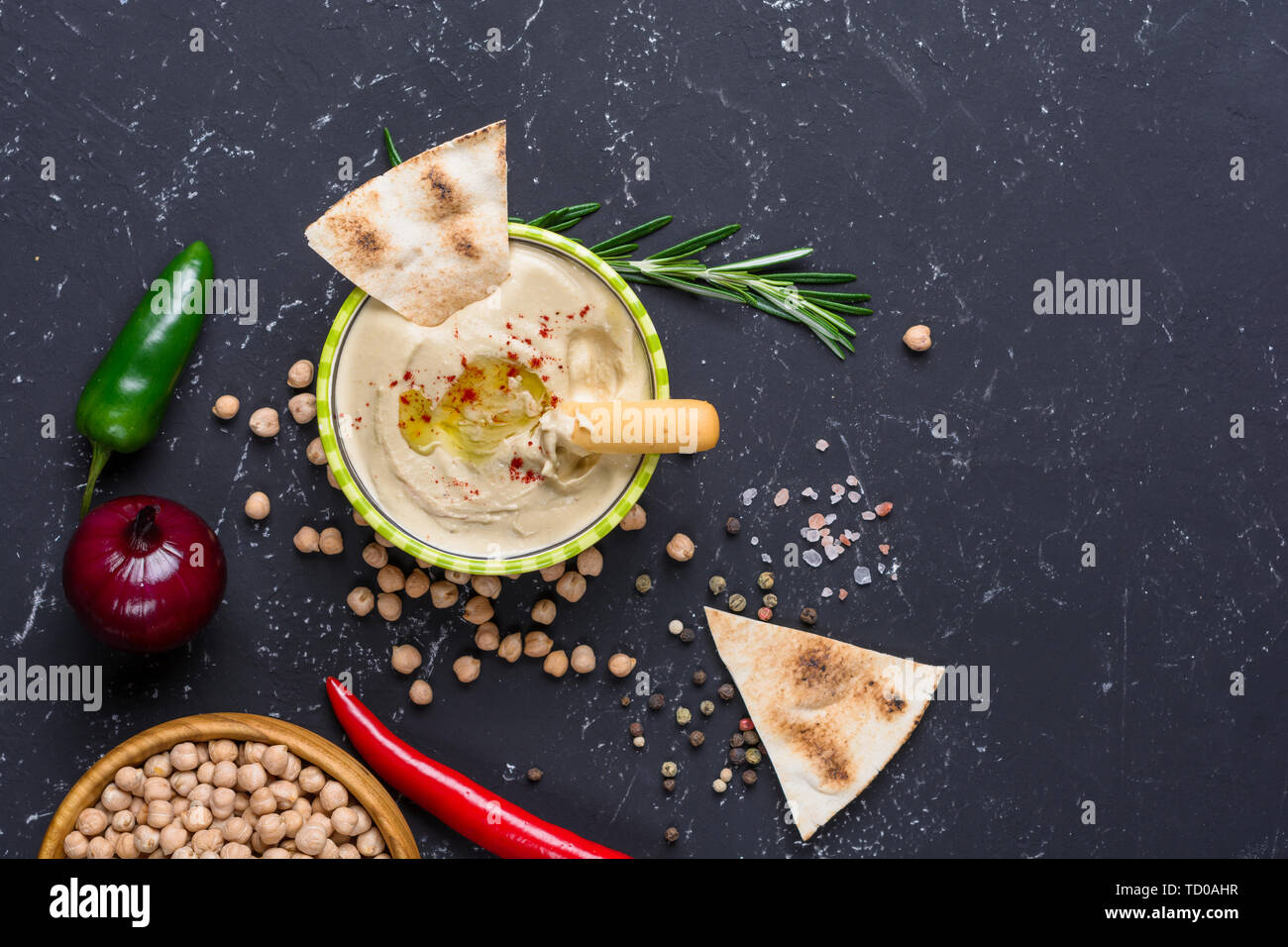 Homemade hummus with pita and grissini bread sticks, chilli, jalapeno