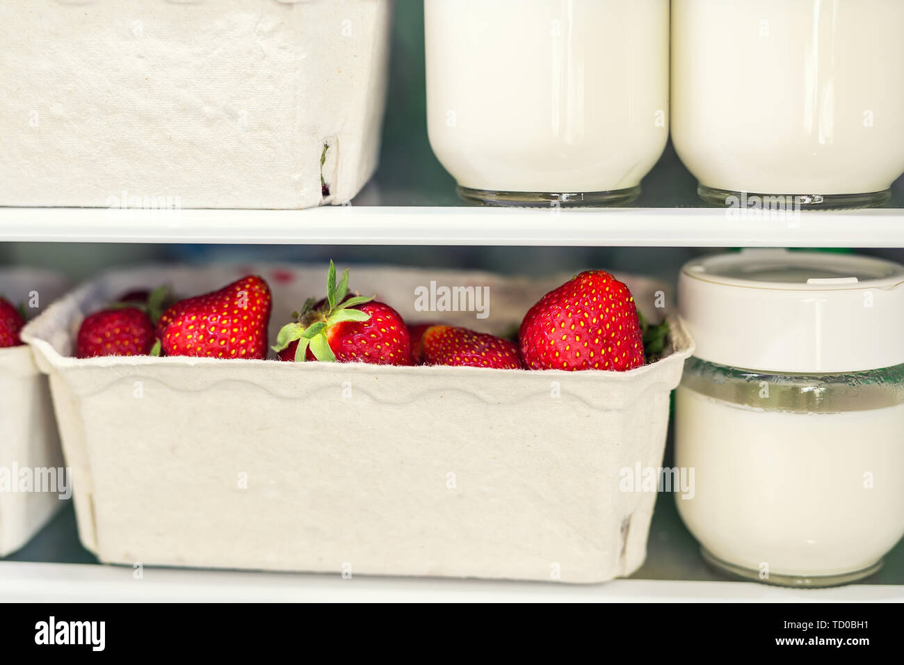 Refrigerator shelf with organic juicy strawberries in bio recycled paper boxes and homemade