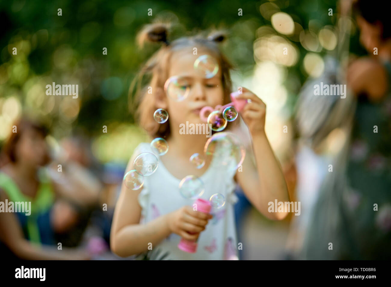 Blurred Little Cute Baby Girl Is Making Soap Bubbles In The Park