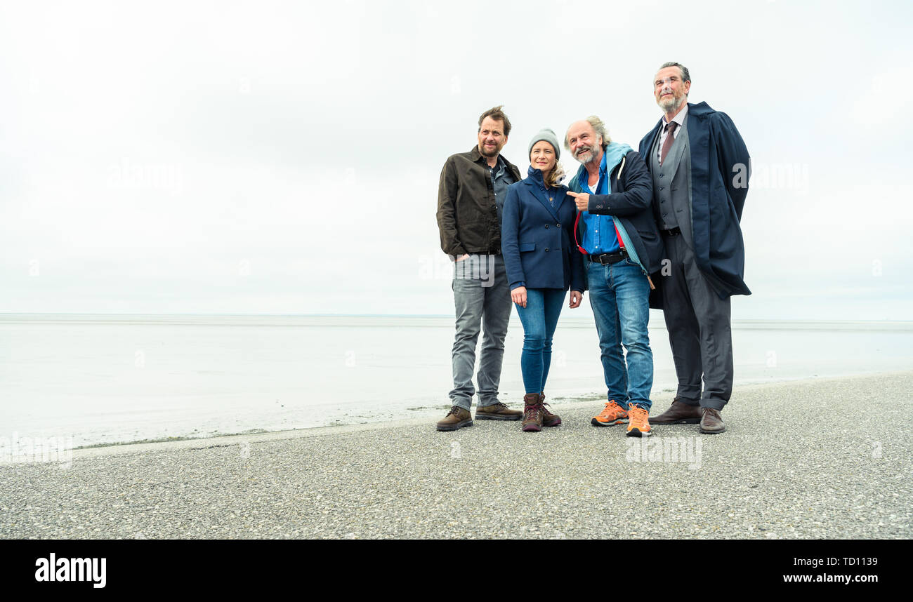 Norddeich, Germany. 11th June, 2019. Kai Maertens (as Ubbo Heide; l-r), Julia Jentsch (as Ann Kathrin Klaasen) and Christian Erdmann (as Frank Eller) sit on the dike during the press date for the Saturday thriller 'Ostfriesengrab'. The fourth film in the Ostfriesland crime series is based on the novel of the same name by Klaus-Peter Wolf (about dpa 'successful author Klaus-Peter Wolf provides material for new ZDF crime thriller'). Credit: Mohssen Assanimoghaddam/dpa/Alamy Live News Stock Photo