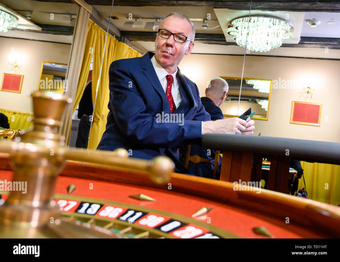 Hameln, Germany. 11th June, 2019. Ludger Pistor, actor in the James Bond film 'Casino Royale' (2006) as Swiss private banker 'Herr Mendel', sits in the exhibition 'James Bond. The power of seduction' in the Museum Hameln at a casino table. The exhibition will run from 12 June 2019 to 10 May 2020. Credit: Christophe Gateau/dpa/Alamy Live News Stock Photo