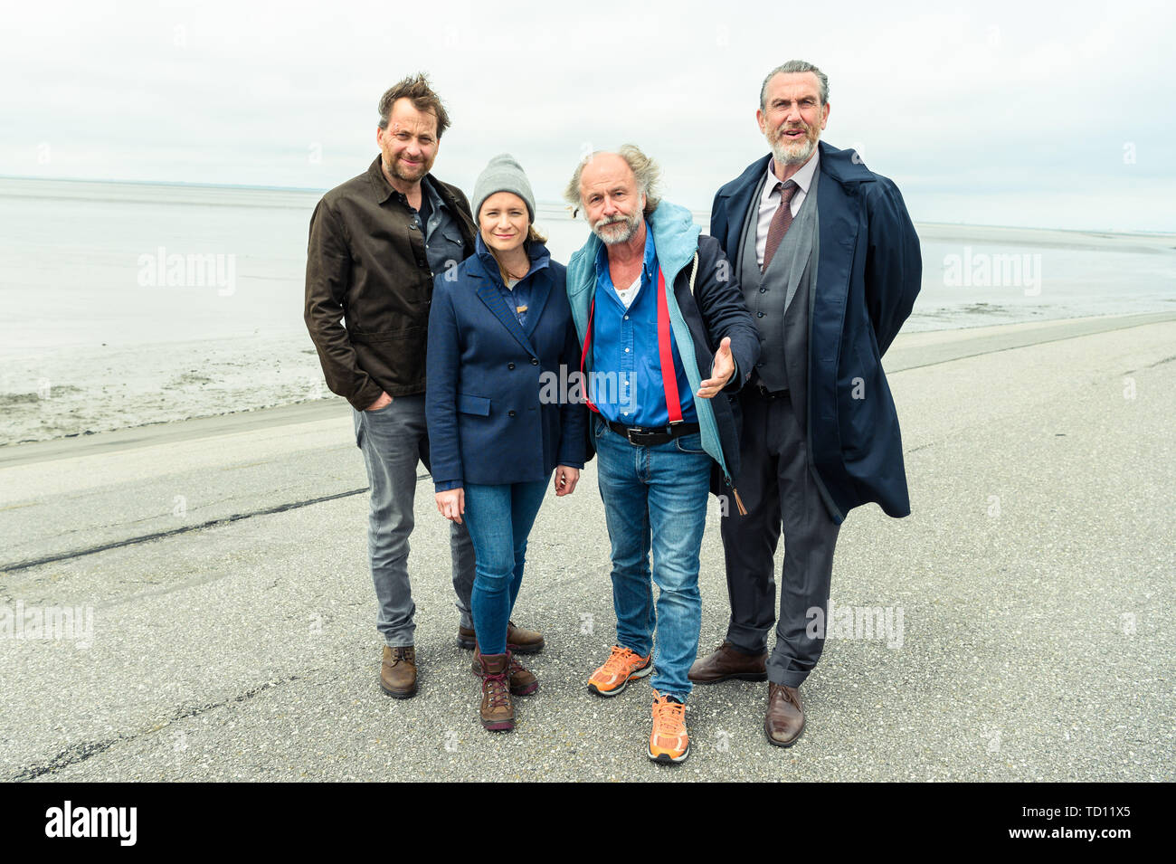 Norddeich, Germany. 11th June, 2019. Christian Erdmann (as Frank Eller), Julia Jentsch (as Ann Kathrin Klaasen), Klaus-Peter Wolf (book author), and Kai Maertens (Ubbo Heide) stand on the dike during the press date for the Saturday thriller 'Ostfriesengrab'. The fourth film in the Ostfriesland crime series is based on the novel of the same name by Klaus-Peter Wolf (about dpa 'successful author Klaus-Peter Wolf provides material for new ZDF crime thriller'). Credit: Mohssen Assanimoghaddam/dpa/Alamy Live News Stock Photo