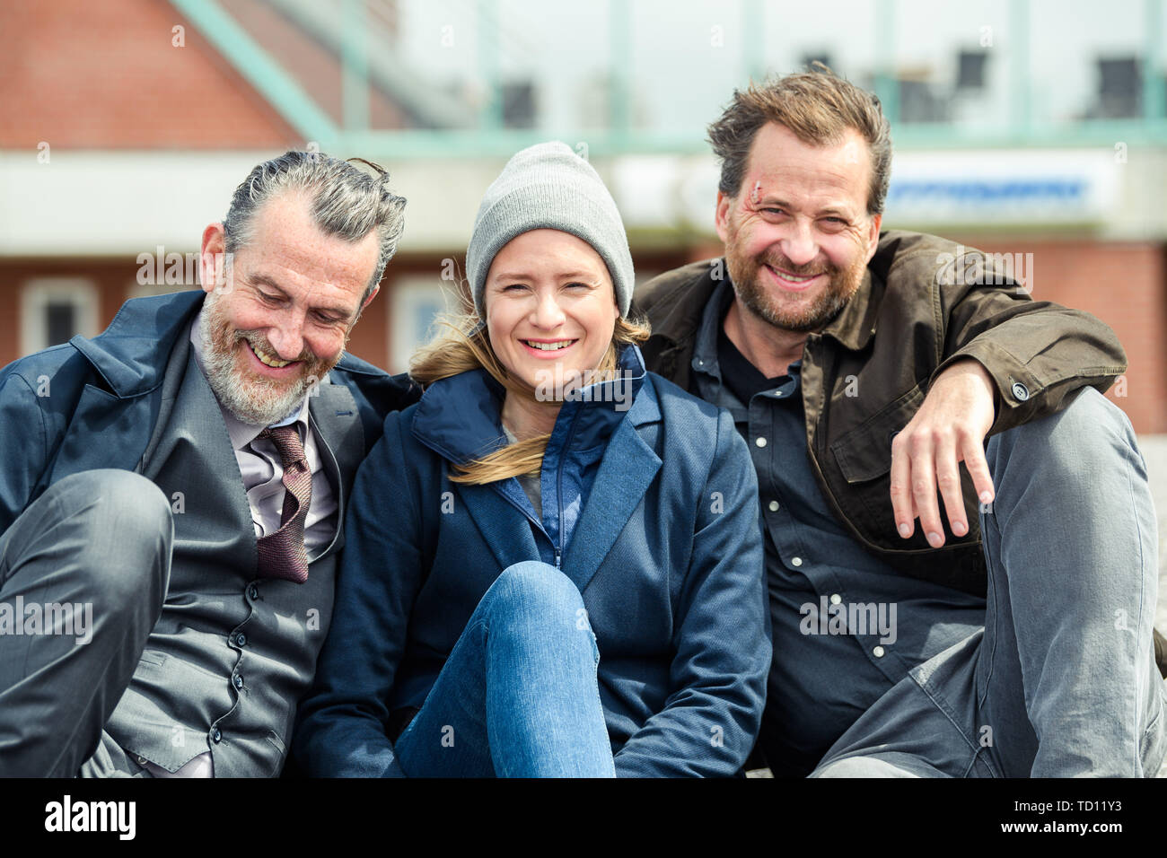Norddeich, Germany. 11th June, 2019. Kai Maertens (as Ubbo Heide; l-r), Julia Jentsch (as Ann Kathrin Klaasen) and Christian Erdmann (as Frank Eller) sit on the dike during the press date for the Saturday thriller 'Ostfriesengrab'. The fourth film in the Ostfriesland crime series is based on the novel of the same name by Klaus-Peter Wolf (about dpa 'successful author Klaus-Peter Wolf provides material for new ZDF crime thriller'). Credit: Mohssen Assanimoghaddam/dpa/Alamy Live News Stock Photo