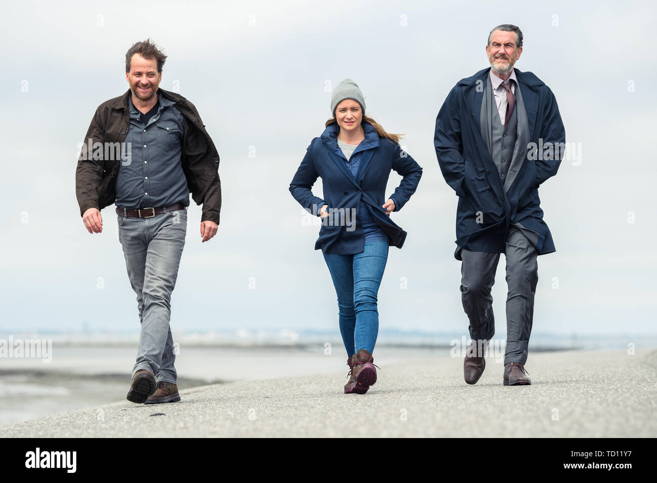 Norddeich, Germany. 11th June, 2019. Christian Erdmann (as Frank Eller; l-r), Julia Jentsch (as Ann Kathrin Klaasen), and Kai Maertens (as Ubbo Heide) walk along the dike during the press conference to the Saturday thriller 'Ostfriesengrab'. The fourth film in the Ostfriesland crime series is based on the novel of the same name by Klaus-Peter Wolf (about dpa 'successful author Klaus-Peter Wolf provides material for new ZDF crime thriller'). Credit: Mohssen Assanimoghaddam/dpa/Alamy Live News Stock Photo