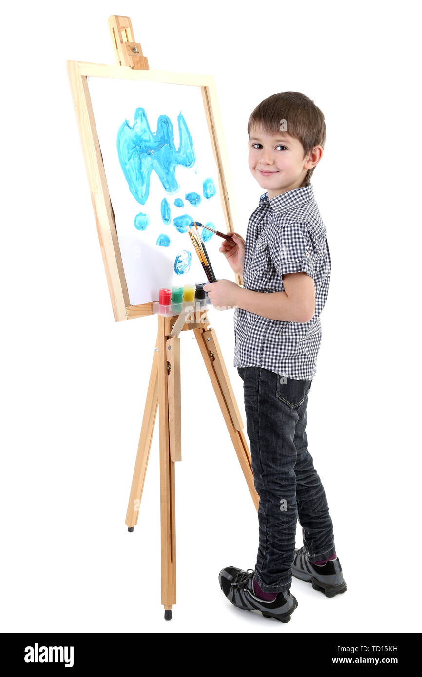 Little boy painting paints picture on easel isolated on white Stock