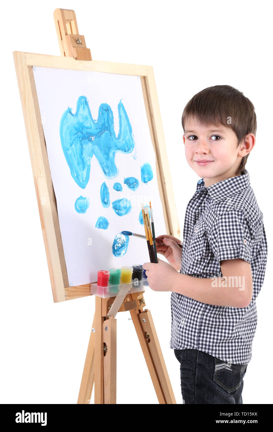 Little boy painting paints picture on easel isolated on white Stock
