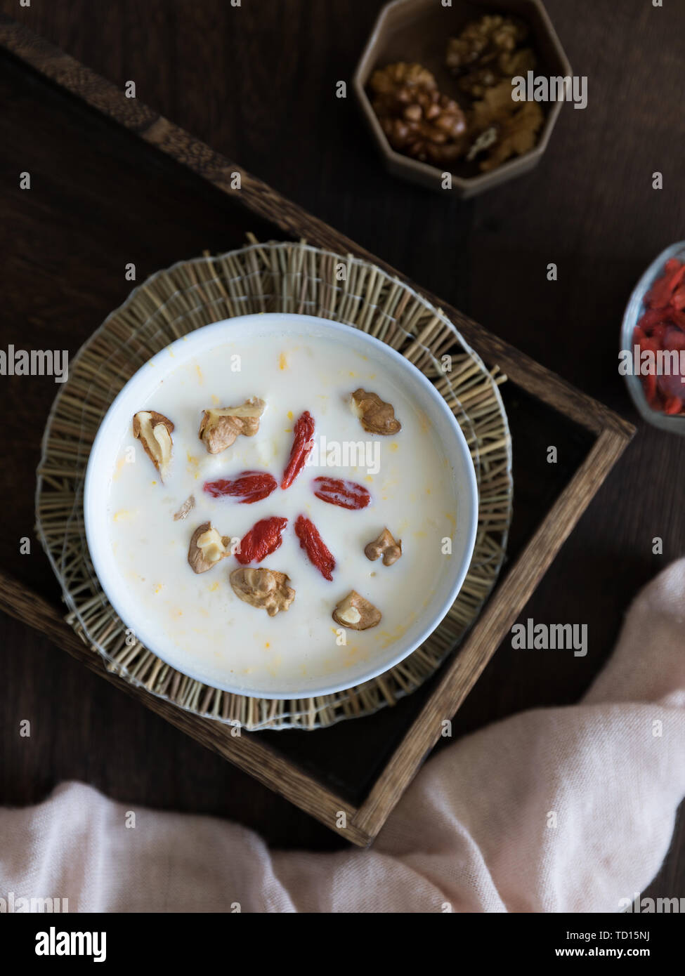A bowl of healthy milk egg glutinous porridge with goji berries and walnuts on a wooden tray. Stock Photo