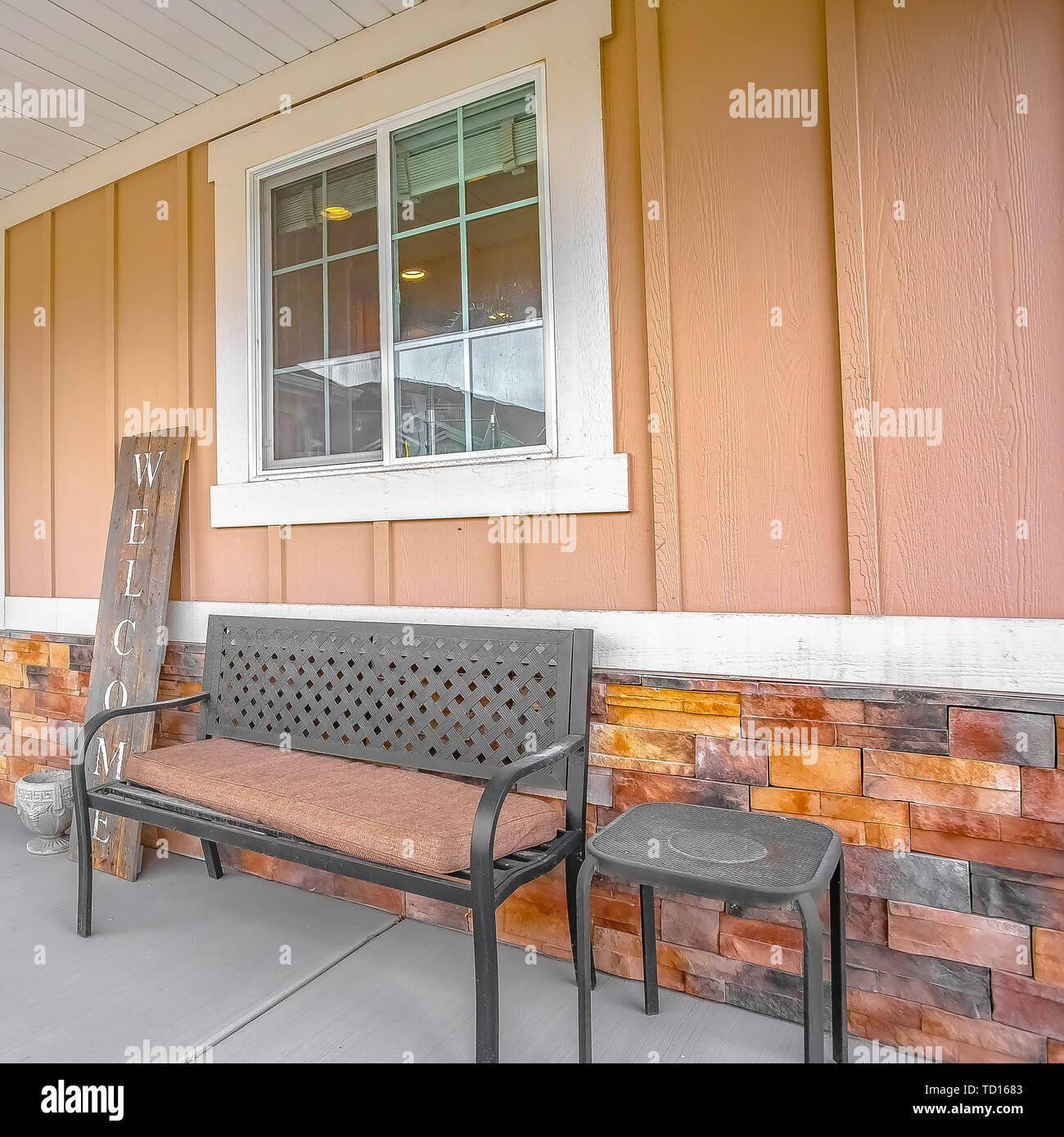 Square Front Porch Of A Home With A Bench And Stool In Front Of