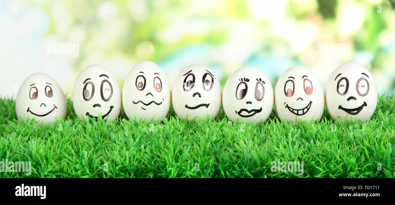 Eggs with funny faces on grass on bright background Stock Photo - Alamy