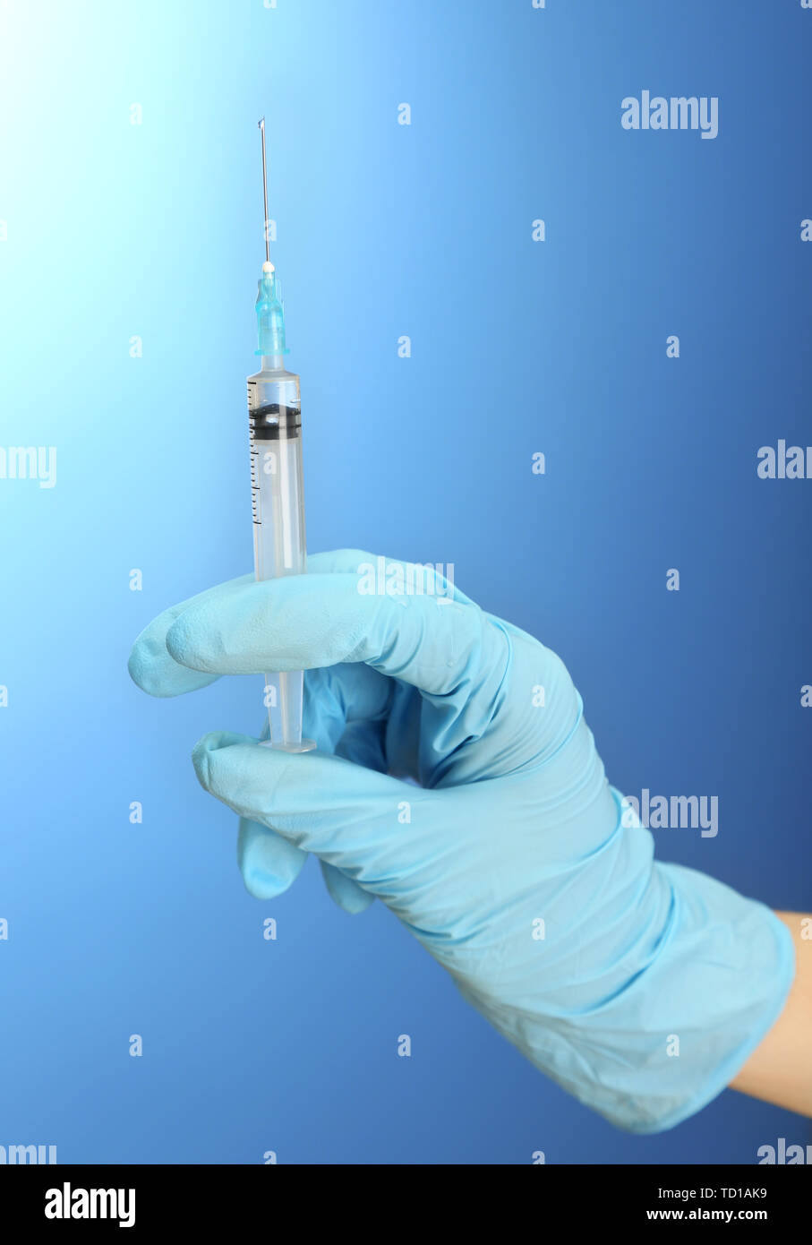 Doctor holding syringe with a vaccine, on blue background Stock Photo ...