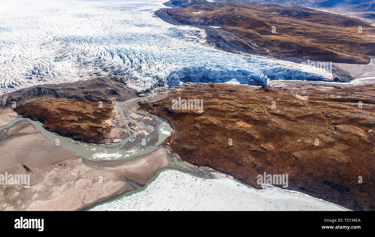 Greenlandic ice sheet melting glacier into river with tundra aerial