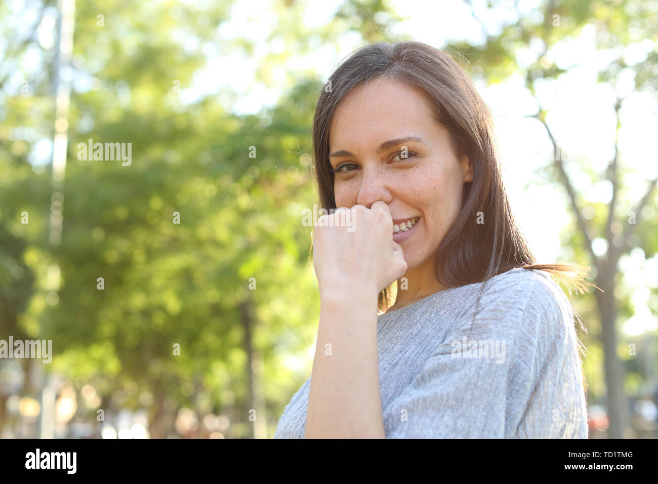 Timid adult woman posing looking at you standing in a park Stock Photo