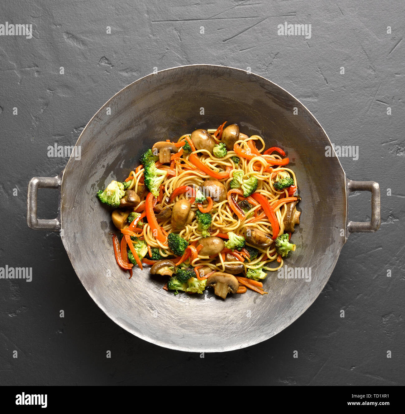 Close up of stir-fry noodles with vegetables in wok pan on black stone background. Top view, flat lay Stock Photo