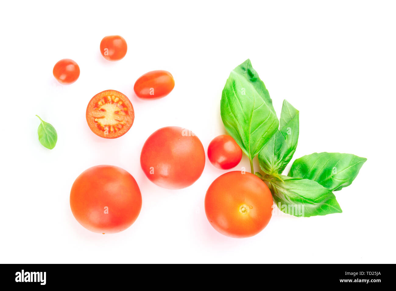 A closeup photo of cherry tomatoes and basil leaves, shot from above on ...