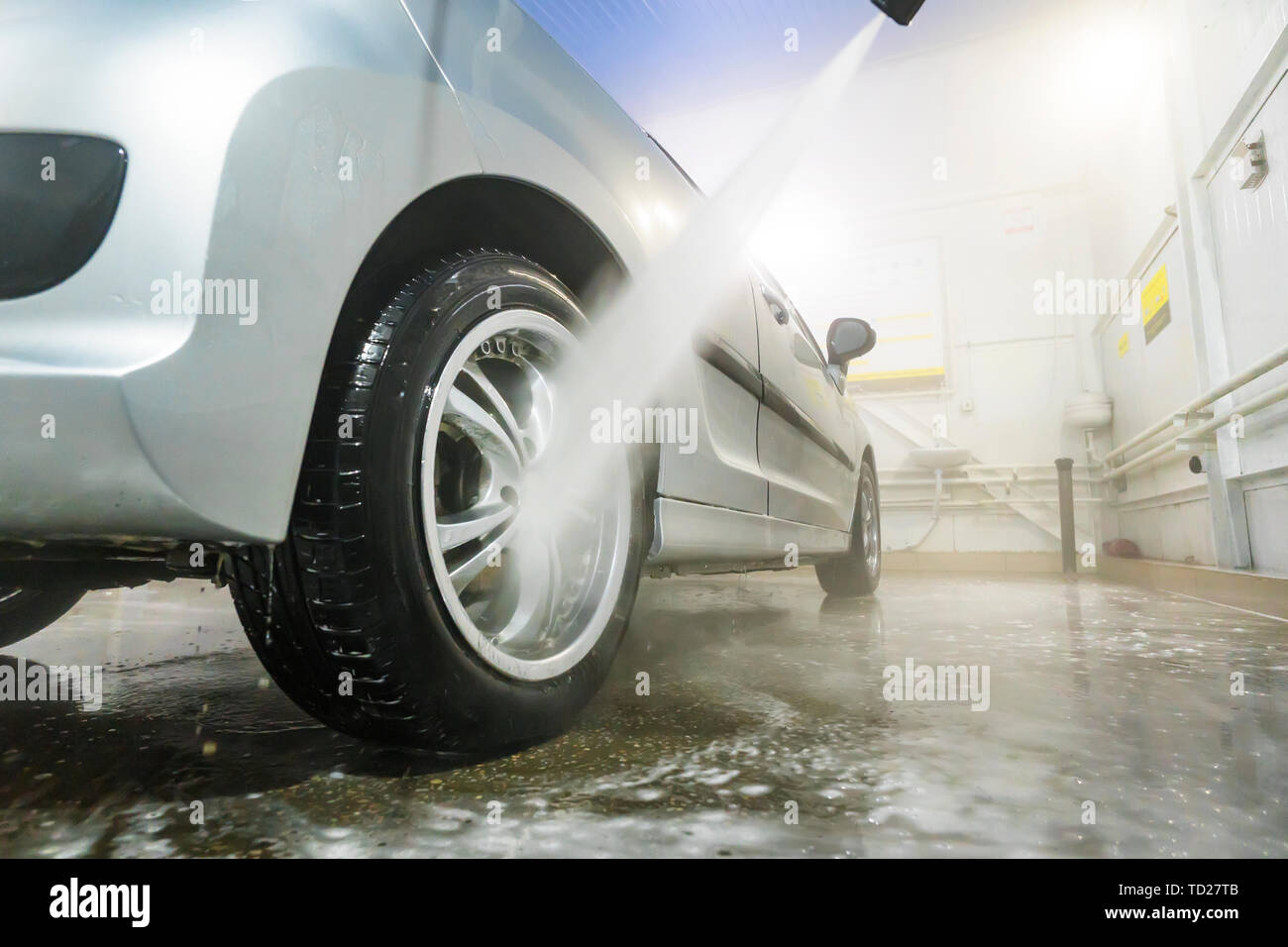 Man cleaning vehicle with high pressure water spray or jet. Car wash