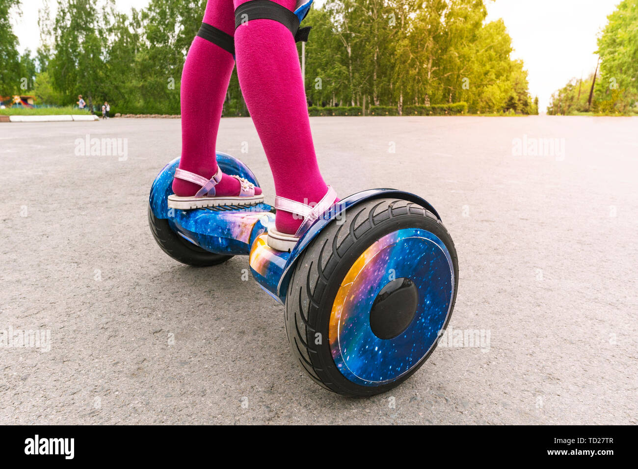 Girl rides on gyroscooter. feet of a little girl in pink pantyhose and sandals are on a GyroScooter Stock Photo
