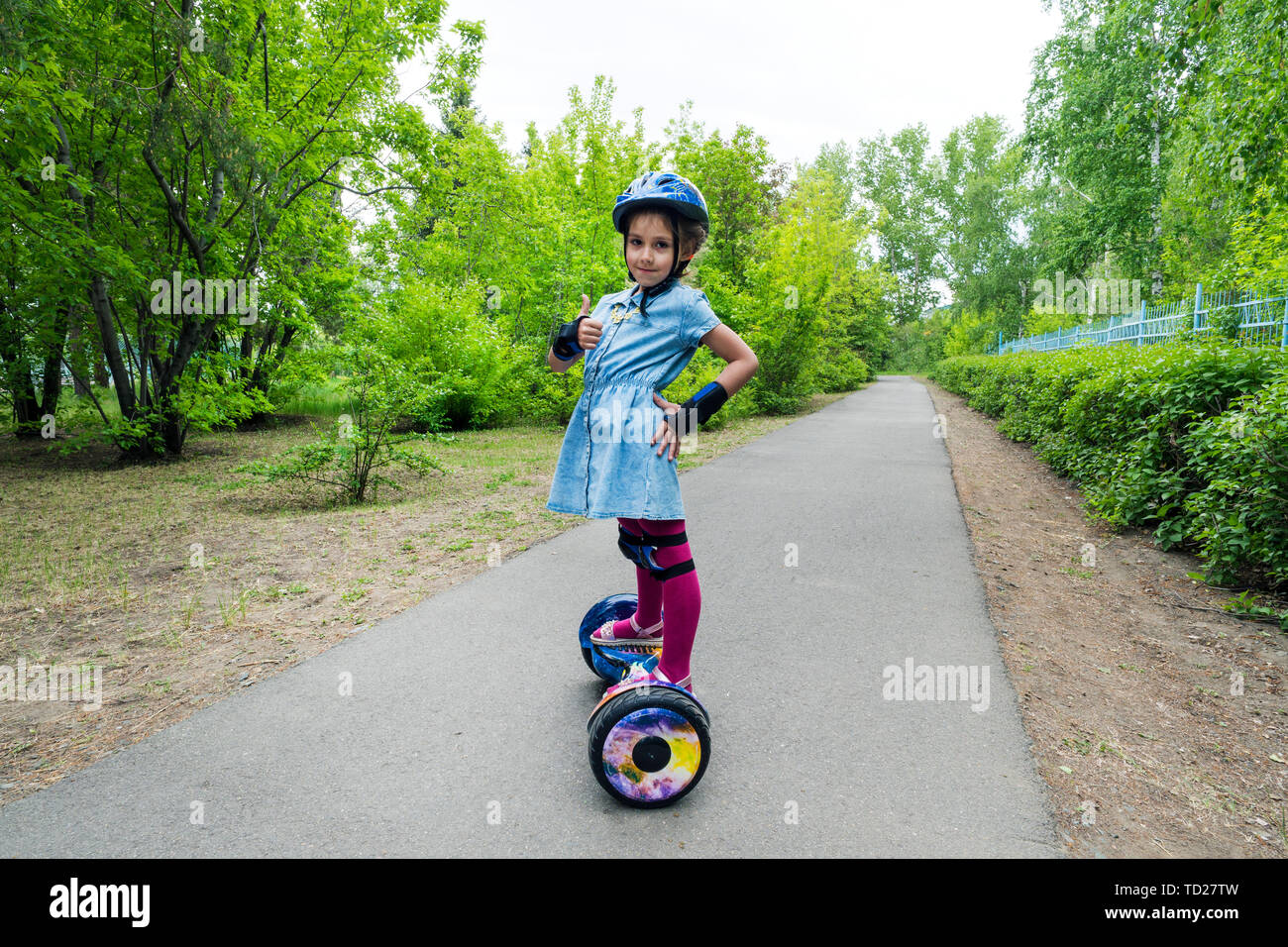 Girl rides on a modern board of self-balancing with a cat in forest in a summer park. Active lifestyle. Electric scooter. Hover-board. New self Stock Photo