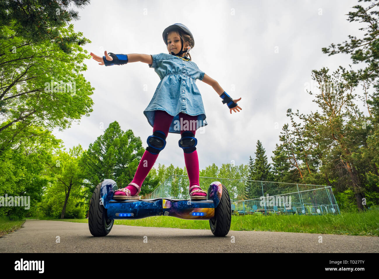 young child girl riding in a city Park on gyroscooter. Summer entertainment in nature. Electric scooter is a modern eco-friendly mode of transport Stock Photo