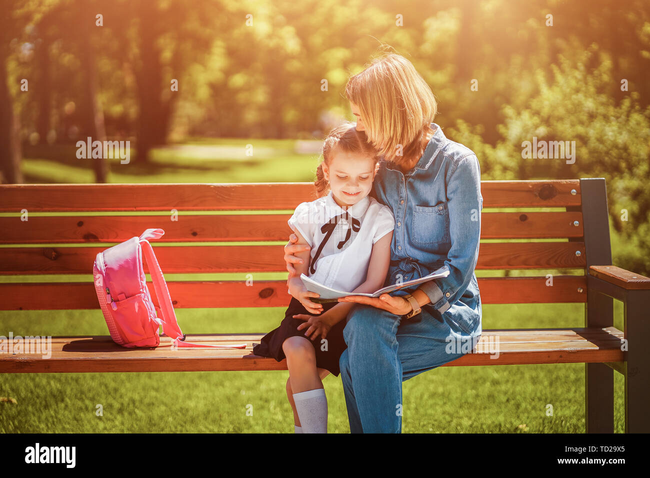 Mother and little daughter in outdoors public park sitting on the bench ...