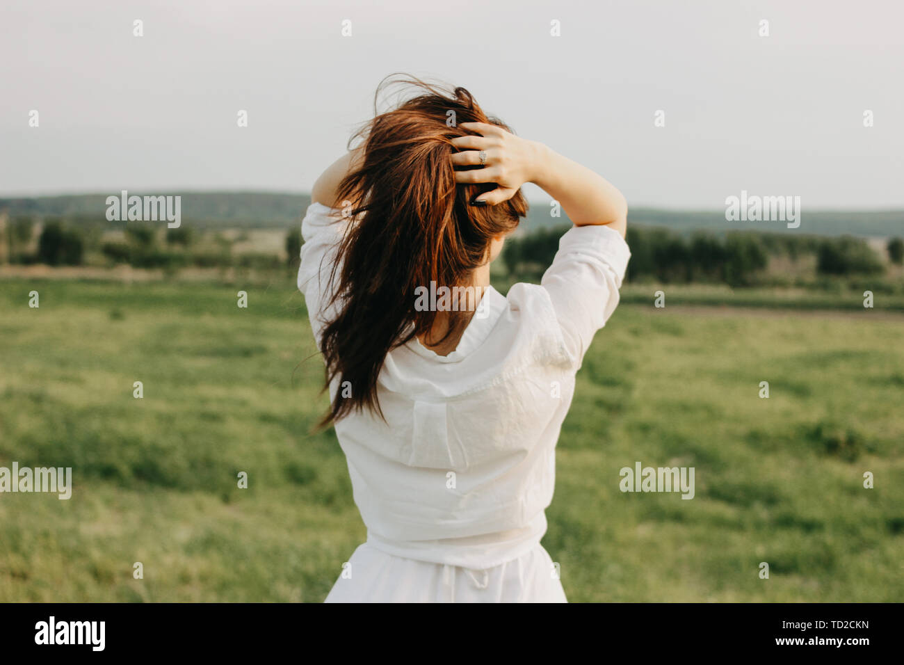 Beautiful carefree long hair girl in white clothes enjoys life in nature  field, view from back. Sensitivity to nature concept Stock Photo - Alamy
