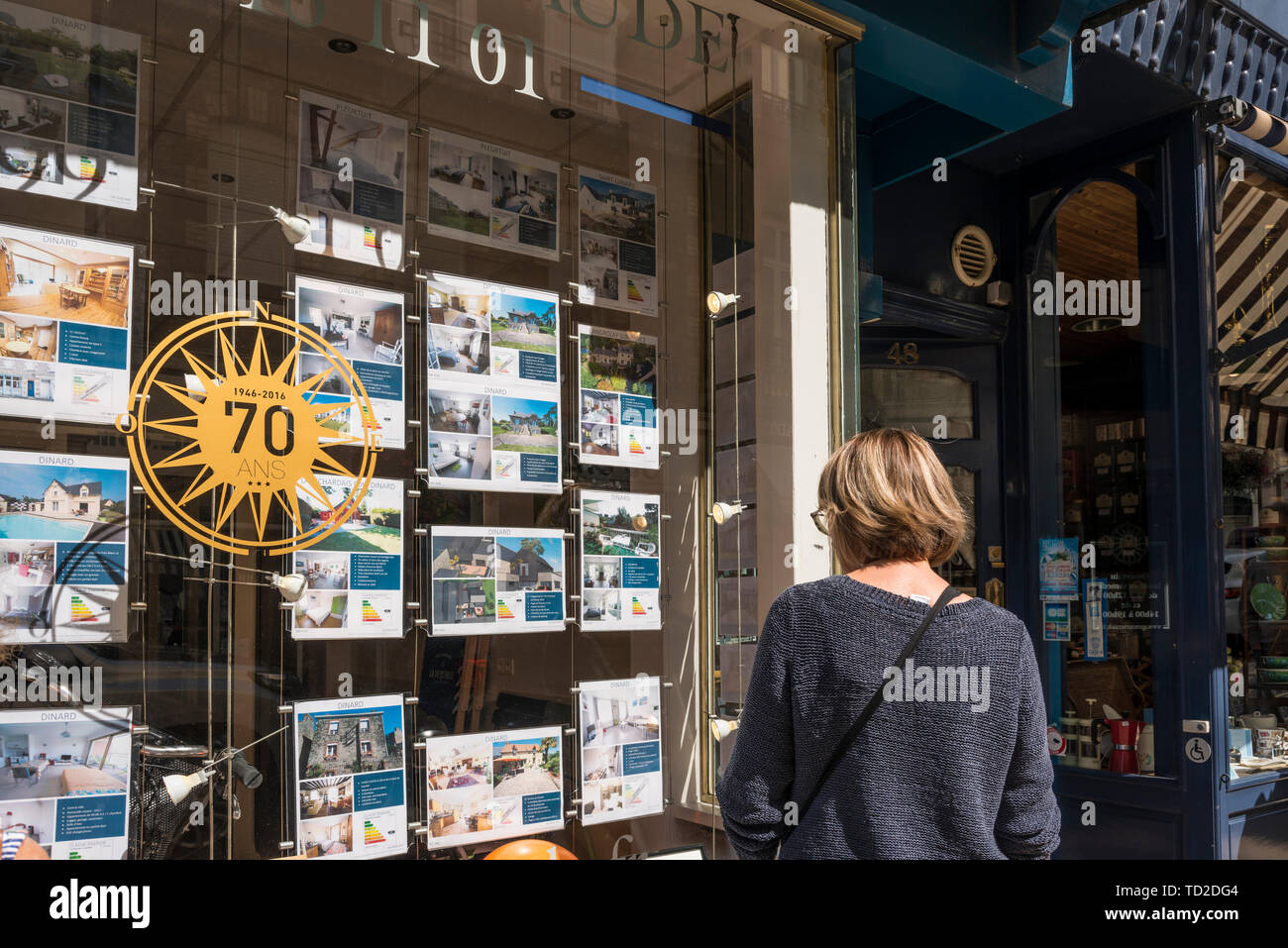 A woman looking at property details on estate agent's window, Dinard, Brittany, France Stock Photo