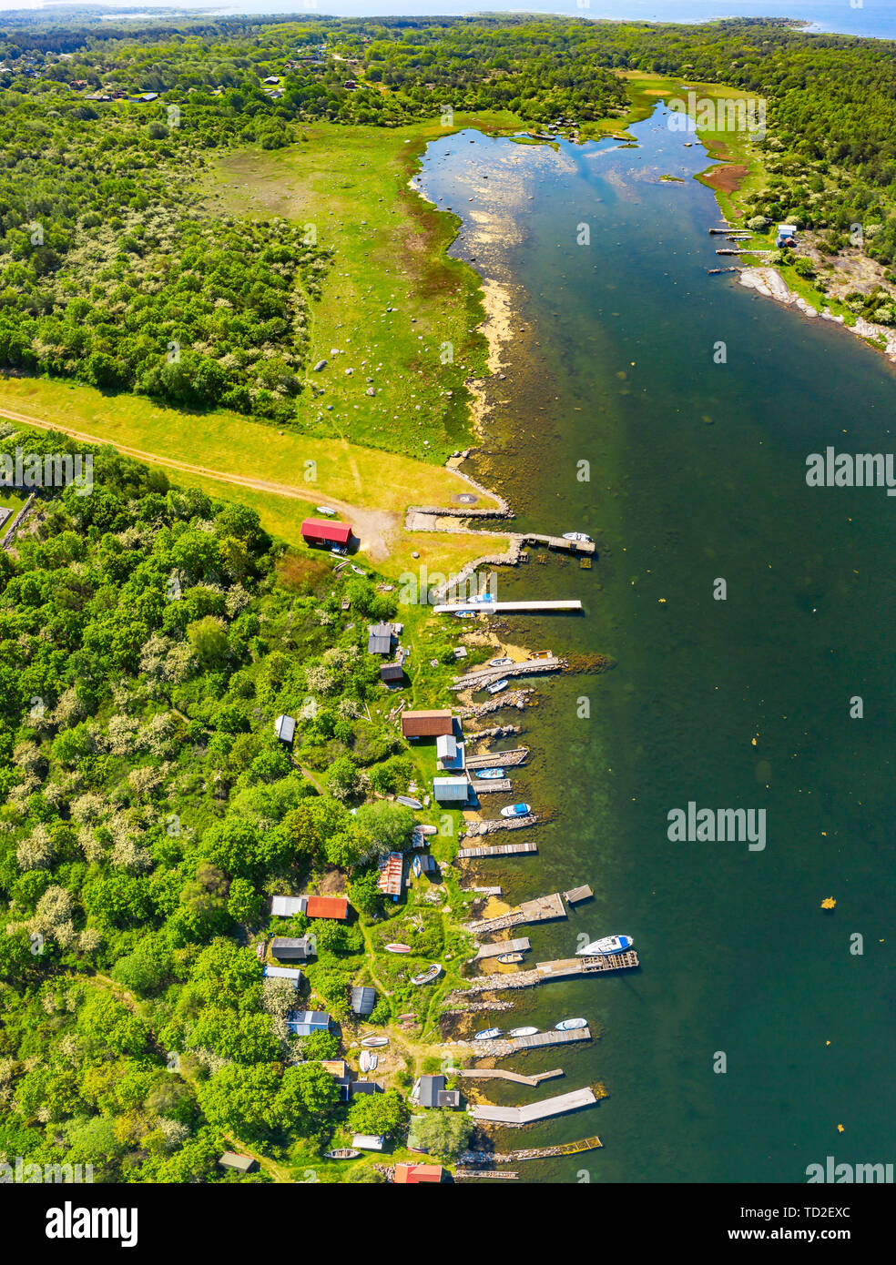 Aerial of coastal landscape with row of jetties lining the shore of a bay. Location Hasslo island in Blekinge archipelago, Sweden. Stock Photo