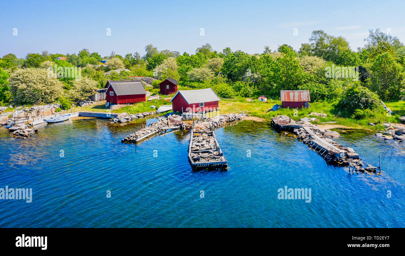 Stone filled jetties and fishing sheds seen from the sea. Location Hasslo island in Blekinge archipelago, Sweden. Stock Photo