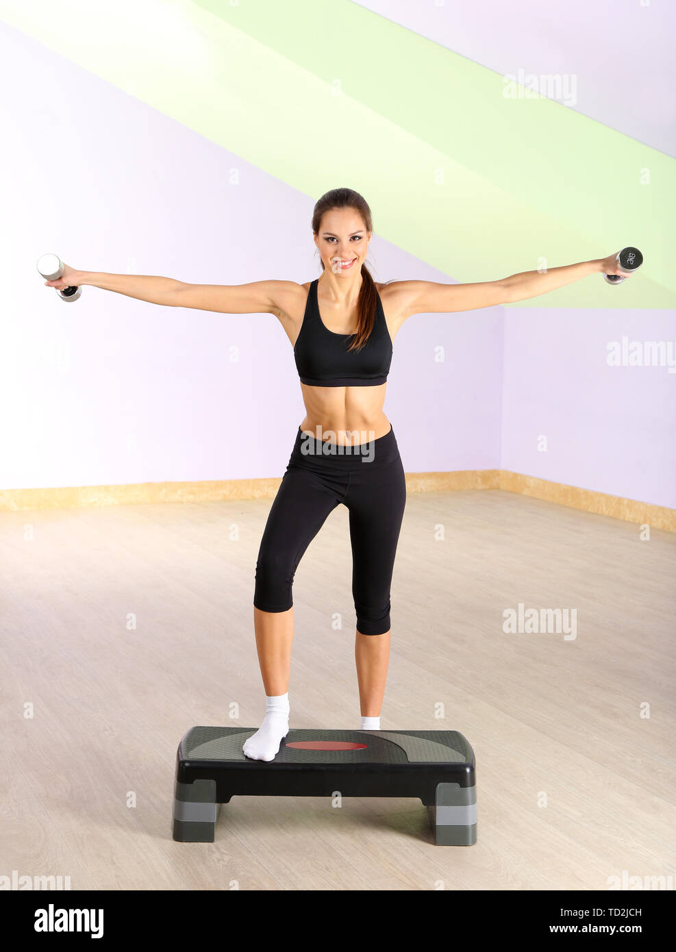Young woman doing fitness exercises on stepper at gymnasium Stock Photo