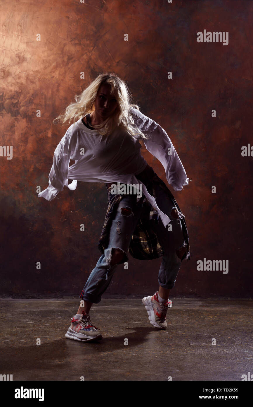 Photo of young dancing blonde woman in ripped jeans and sneakers on ...