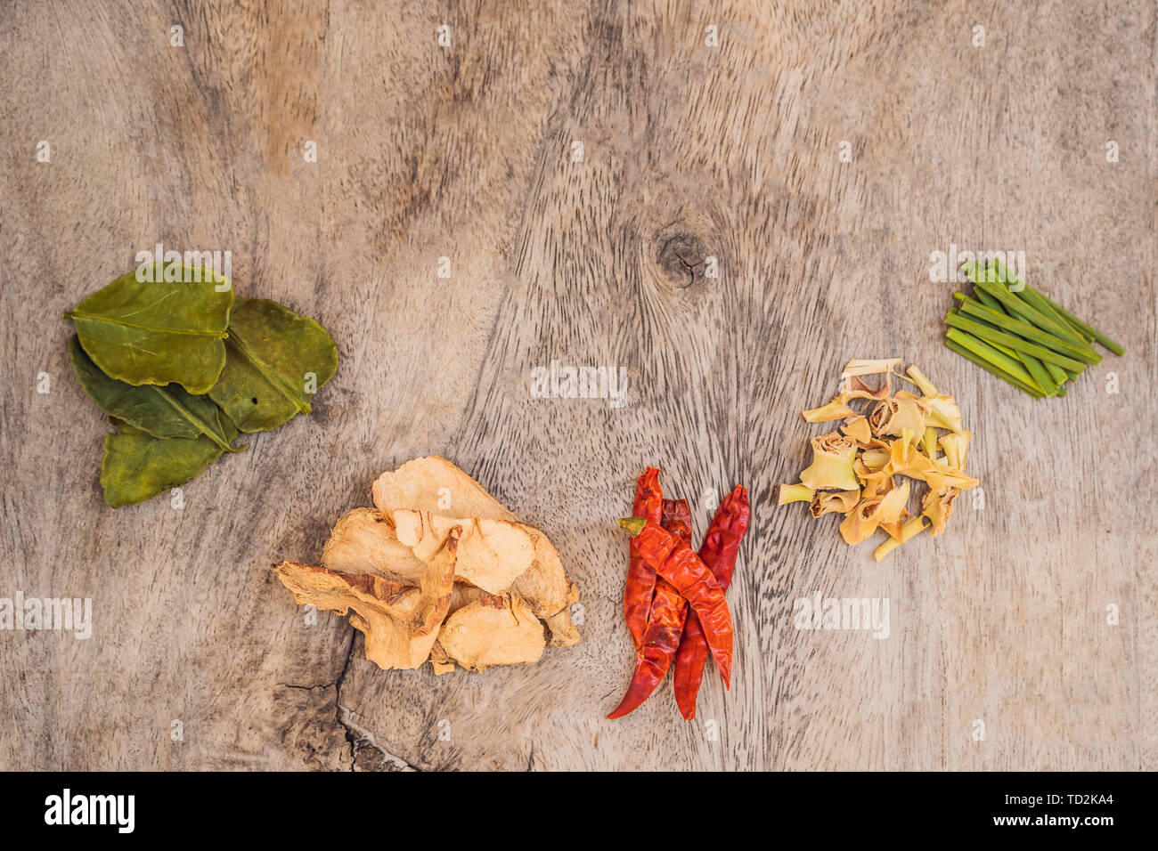 Ingredients for popular Thai soup Tom-yum kung. Lime, galangal, red chili, cherry tomato, lemongrass and kaffir lime leaf on black board . Flat lay Stock Photo