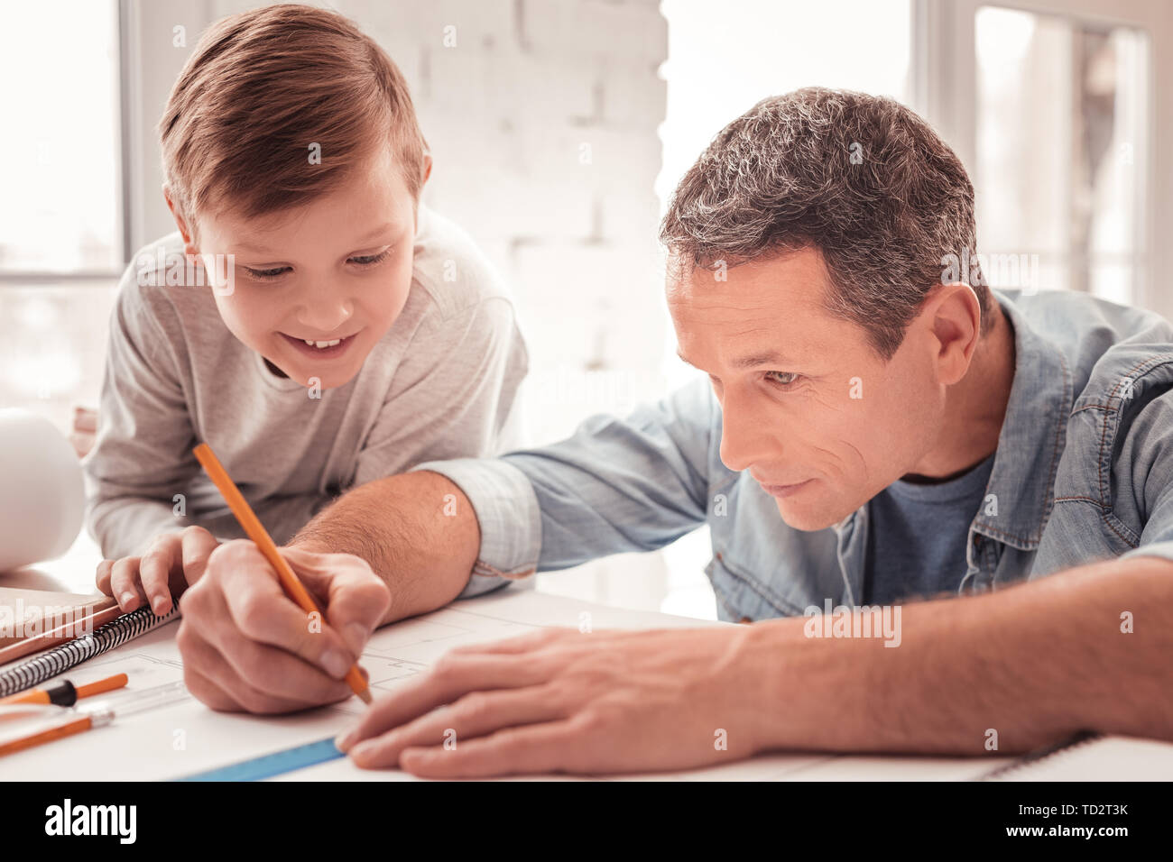 Blonde-haired son watching his father drawing figures for geometry class Stock Photo