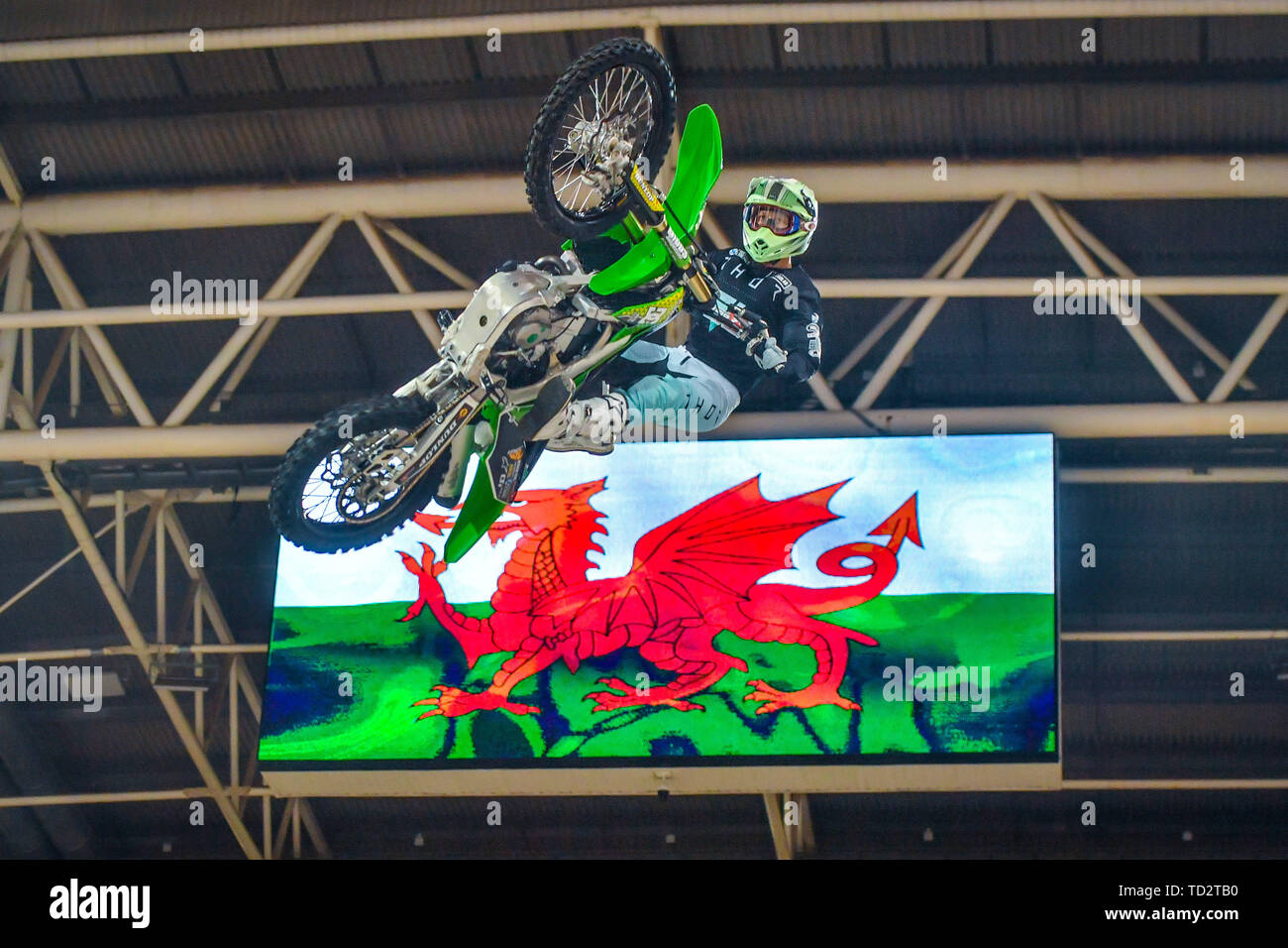 A motor bike rider jumps pulls a trick in front of an image of the Welsh  flag at the launch of the Nitro World Games freestyle motor cross event, at  the Principality