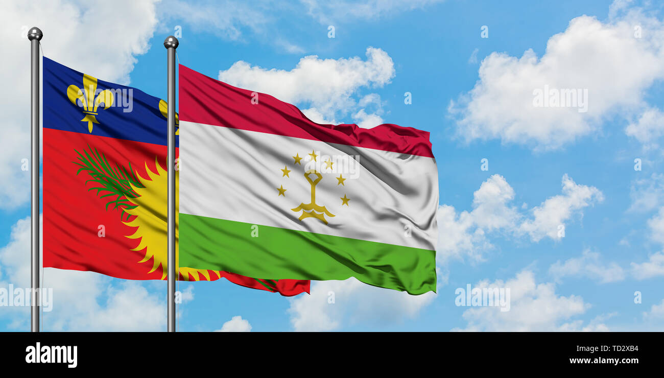 Guadeloupe and Tajikistan flag waving in the wind against white cloudy blue sky together. Diplomacy concept, international relations. Stock Photo