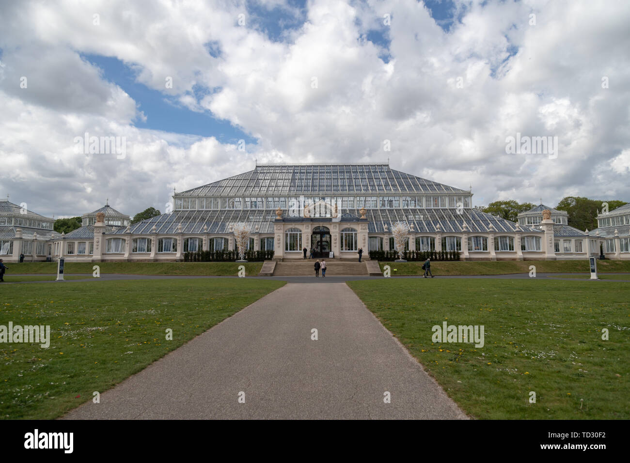 A wide view of the Temperate House with a bright cloudy sky in Kew Gardens. Stock Photo