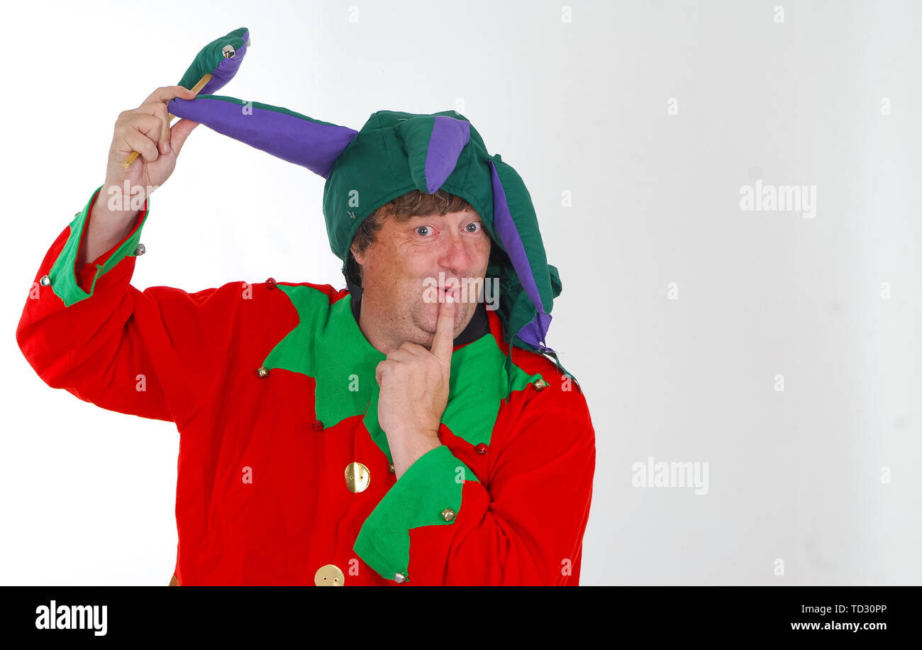A portrait of a middle aged man dressed as a jester in a foolish pose and with a silly expression against a white background Stock Photo
