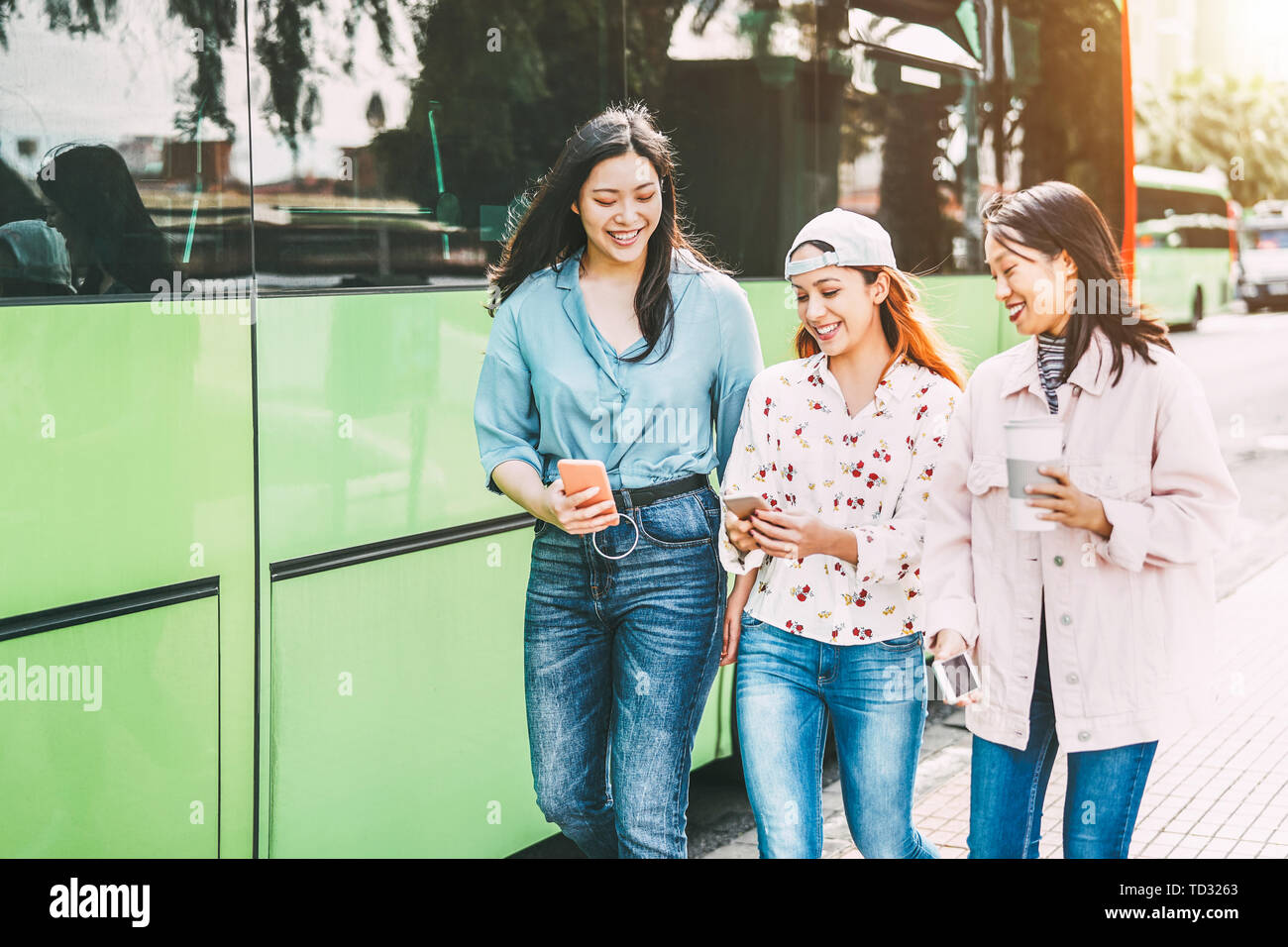 Happy Asian friends using mobile phone outdoor Young millennial people having fun with new