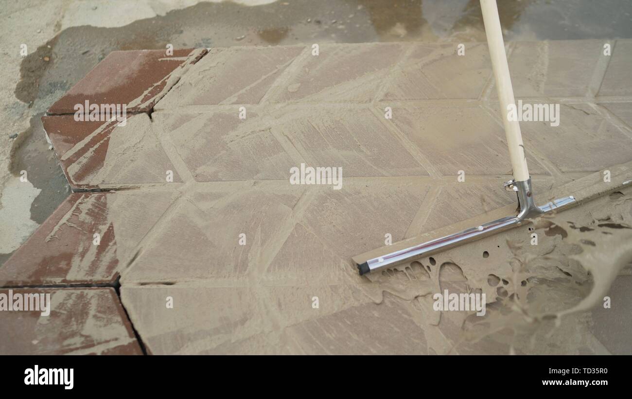 Worker hand with bucket pouring cement for tiles installation making on