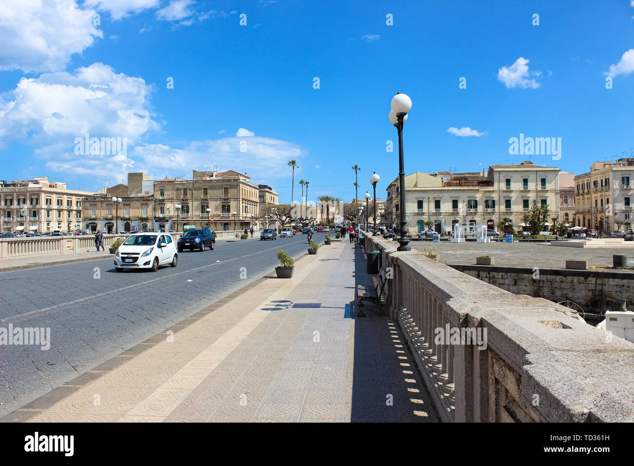 Syracuse, Sicily, Italy - Apr 10th 2019: Bridge connecting Syracuse city and famous Ortygia Island photographed on a sunny day with driving car. Beautiful Ortigia is a popular tourist spot. Stock Photo