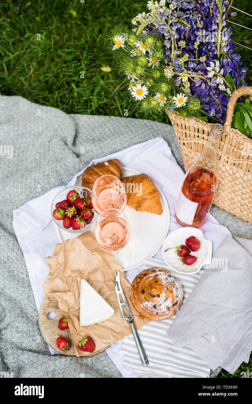 Beautiful summer picnic with strawberries, cheese and rose wine on the lawn  in the city park, outdoor dinner decoration Stock Photo - Alamy